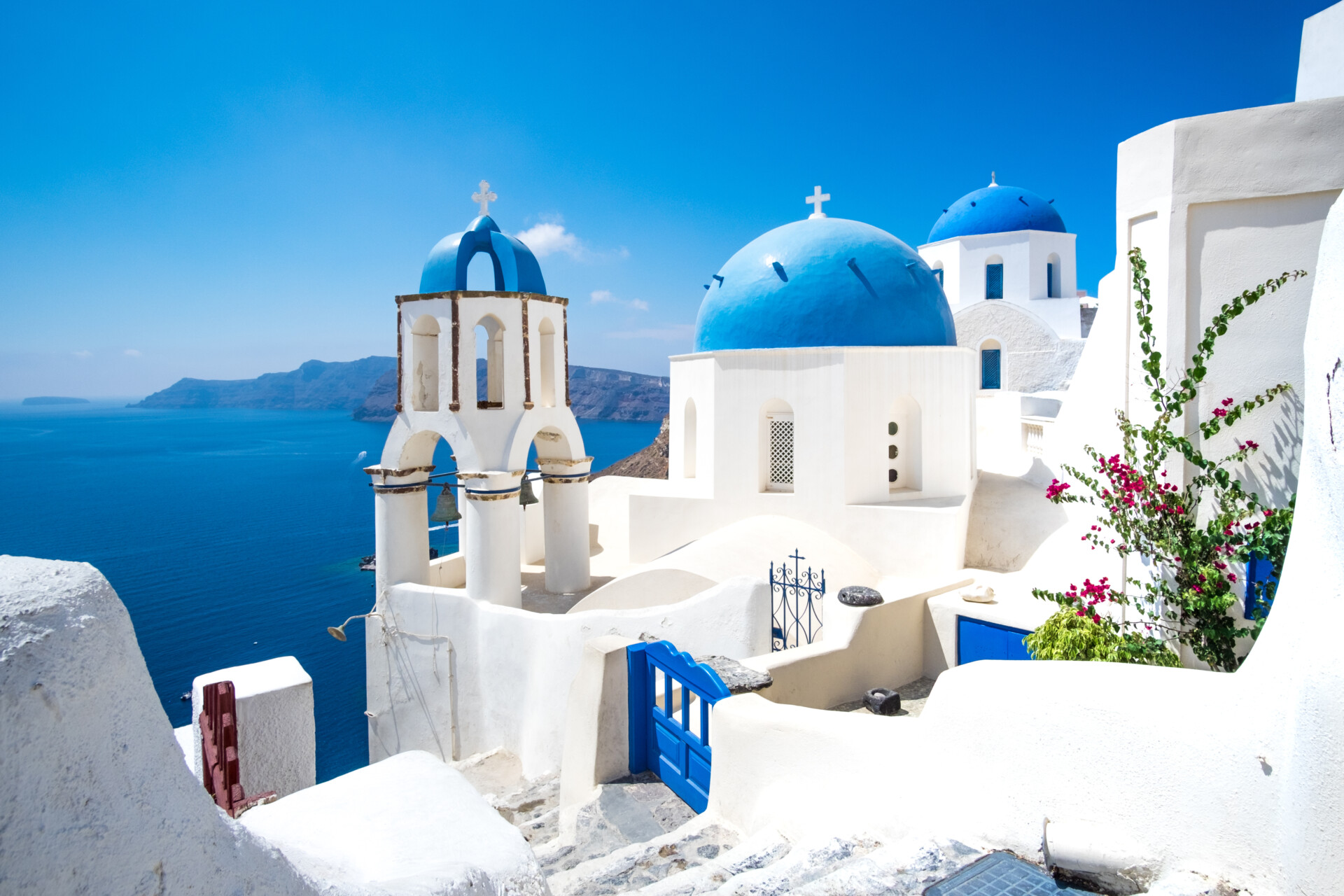 Malerische Aussicht auf traditionelle weiße Kykladenhäuser und blaue Kuppeln im Dorf Oia auf der griechischen Insel Santorini
